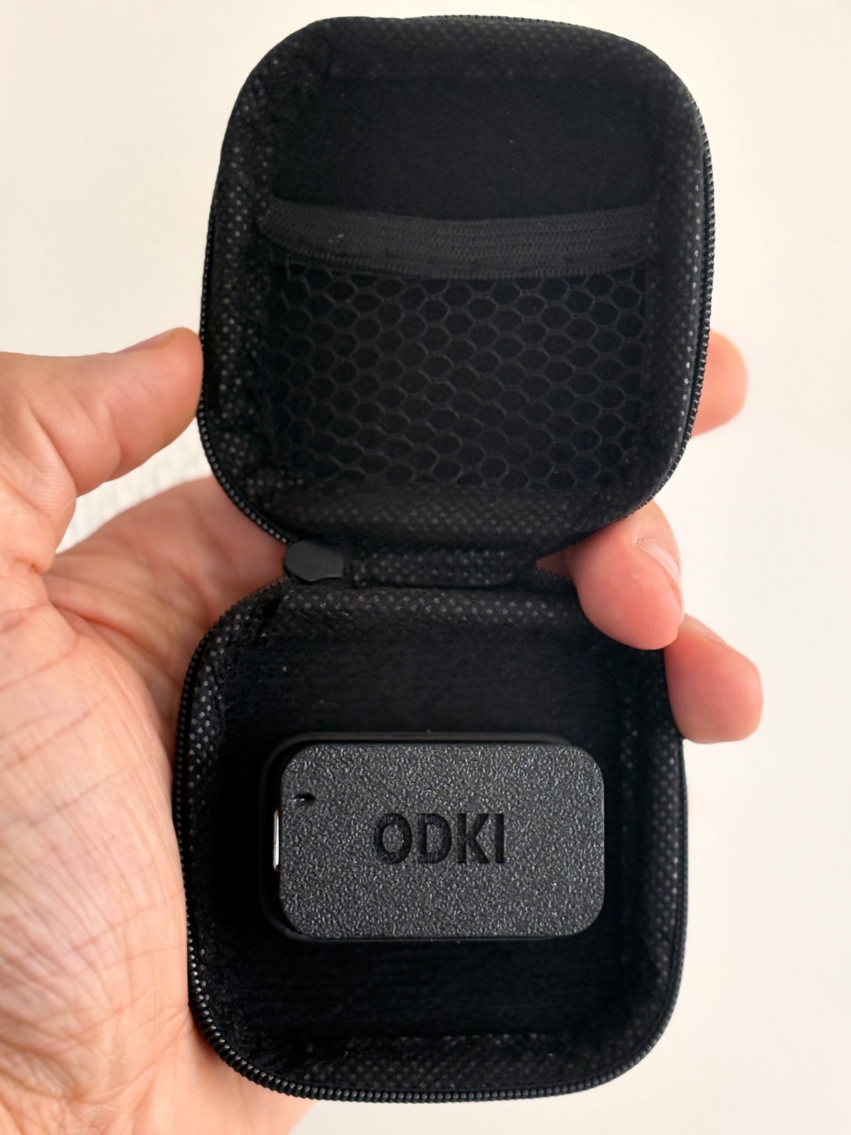 Inside the ODKI‑VBT case, showing the internal magnetic mount with a sensor placed in it for scale