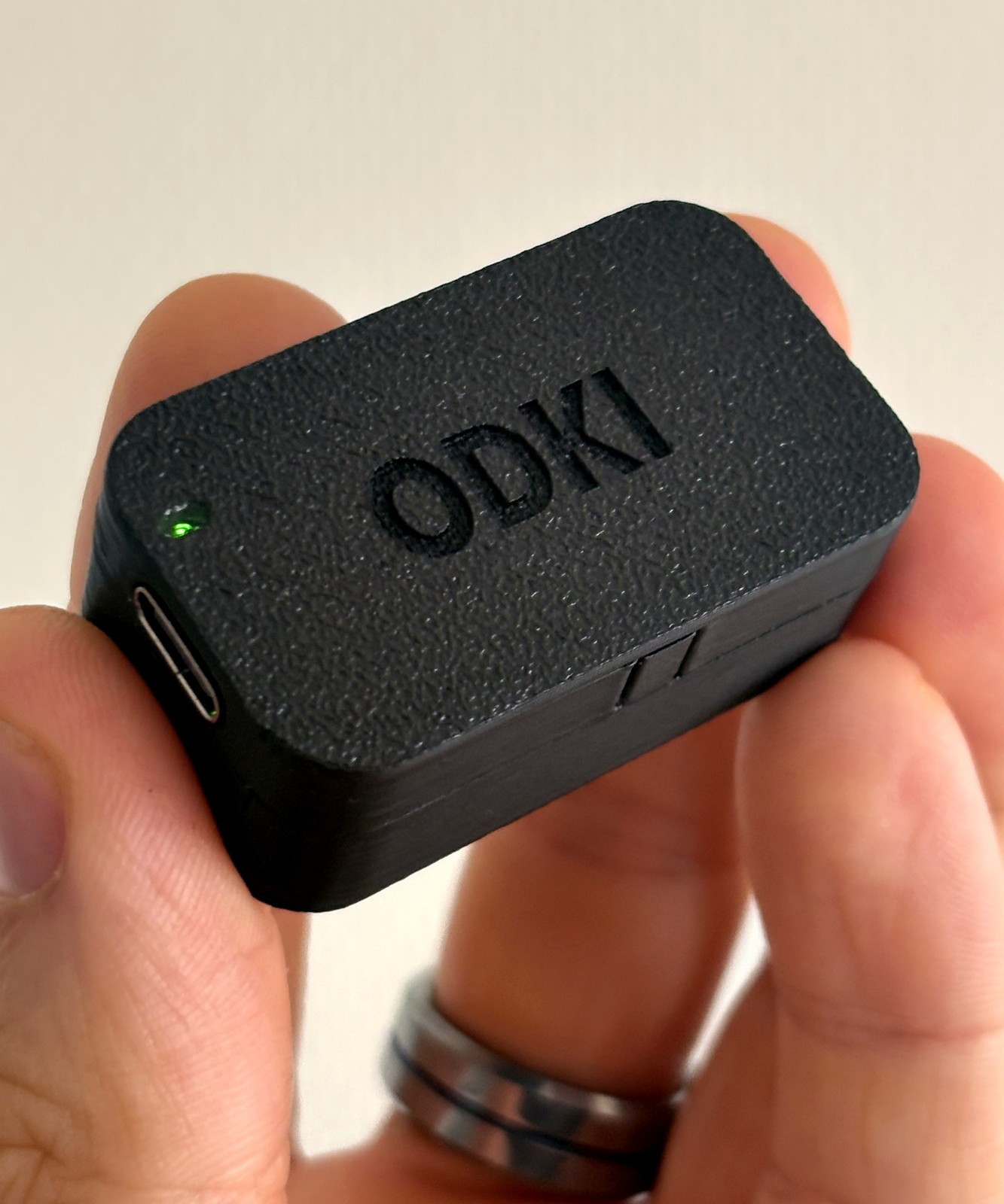 ODKI‑VBT sensor held in hand, showing the engraved logo, USB‑C port and status LED lit green