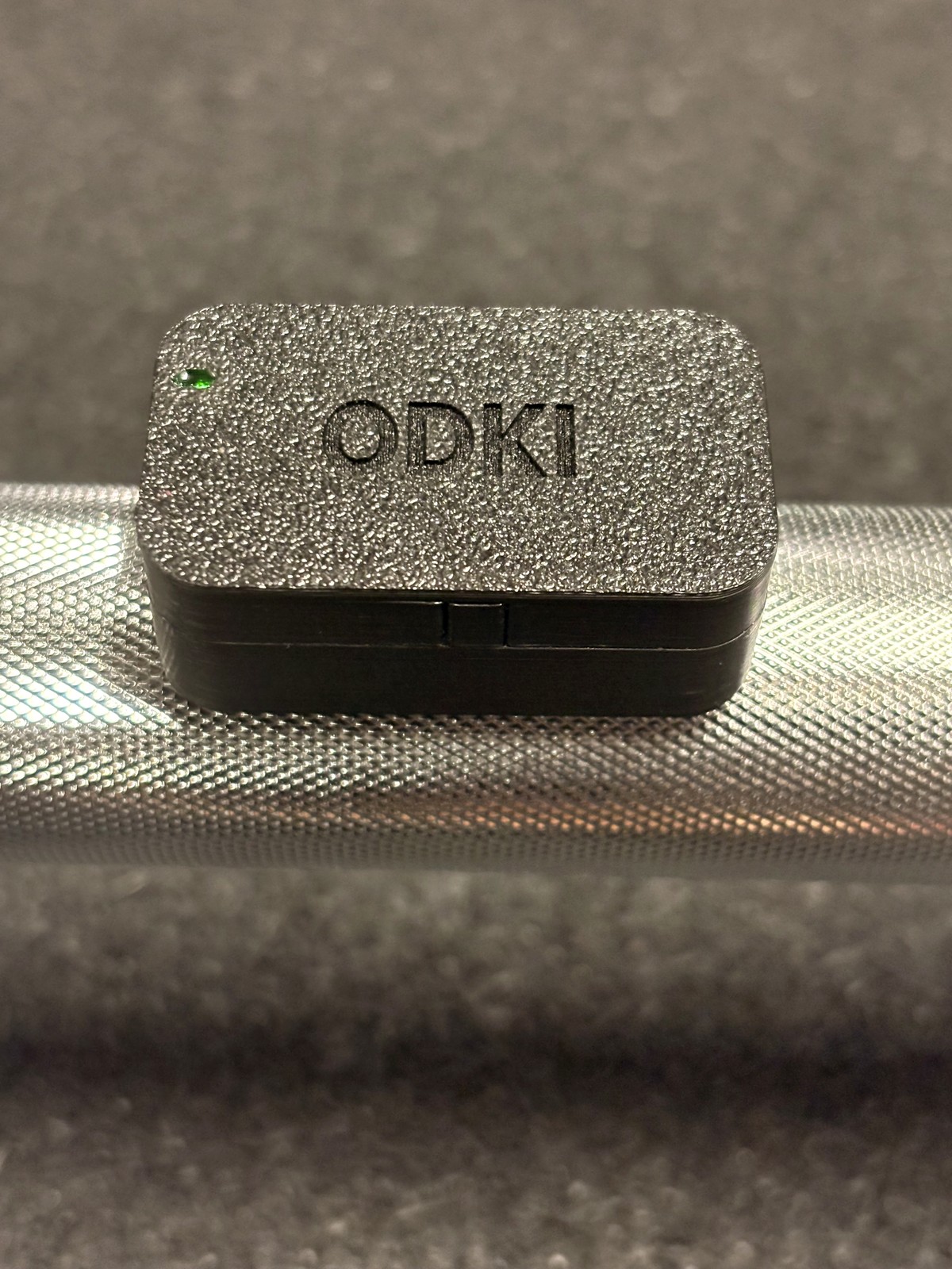 ODKI‑VBT sensor magnetically mounted on a barbell, green status LED lit
